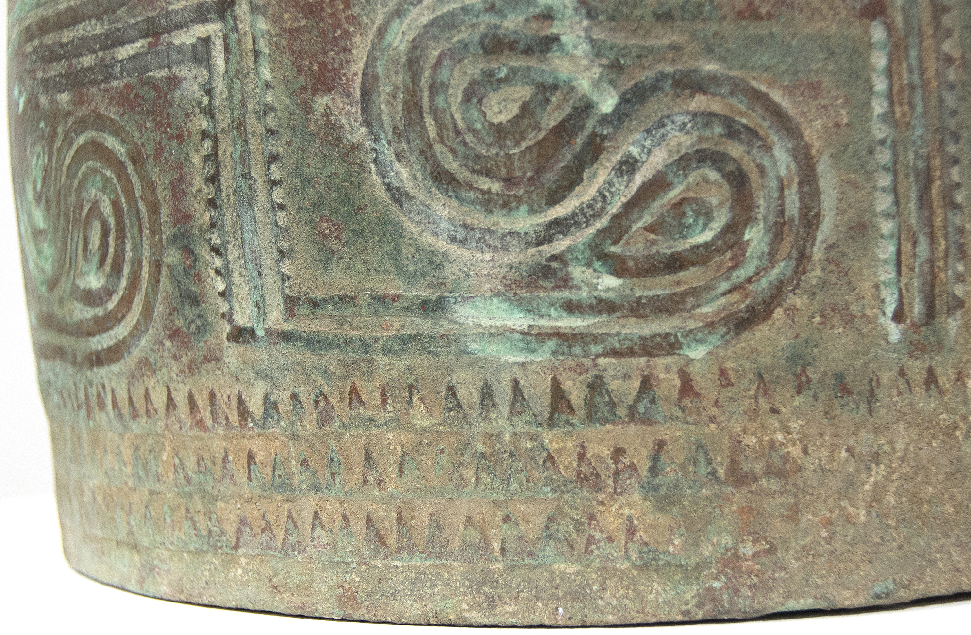 This well preserved bell is one of the largest known bronzes from the Southeast Asian Bronze Age, generally named after the Dongson site in North Vietnam.  The swirling band design is finely and crisply cast. Dongson bronze drums were also reported in South China, Thailand, Laos, West Malaysia, and Indonesia and as Far East as Western Iranian Java. 
<br>
<br>The Dong Son culture is a Bronze age culture including all of southeast Asia and into the Indo-Malaya Archipelago from about 1000 to 1 BC. Centered on the Red River Valley of Vietnam, the Dong Son were sophisticated agriculturalists, raising rice and buffalo. Dong Son probably arose from local Neolithic cultures, such as Phung Nguyen and Dong Dau phases. Dong Son is identified with the Van Lang ruling dynasty, the first ruling dynasty of Vietnam. By the second century BC, impacts from the Han Dynasty in China were being felt and according to historic records, the Dong Son were absorbed into the Han Dynasty territory.