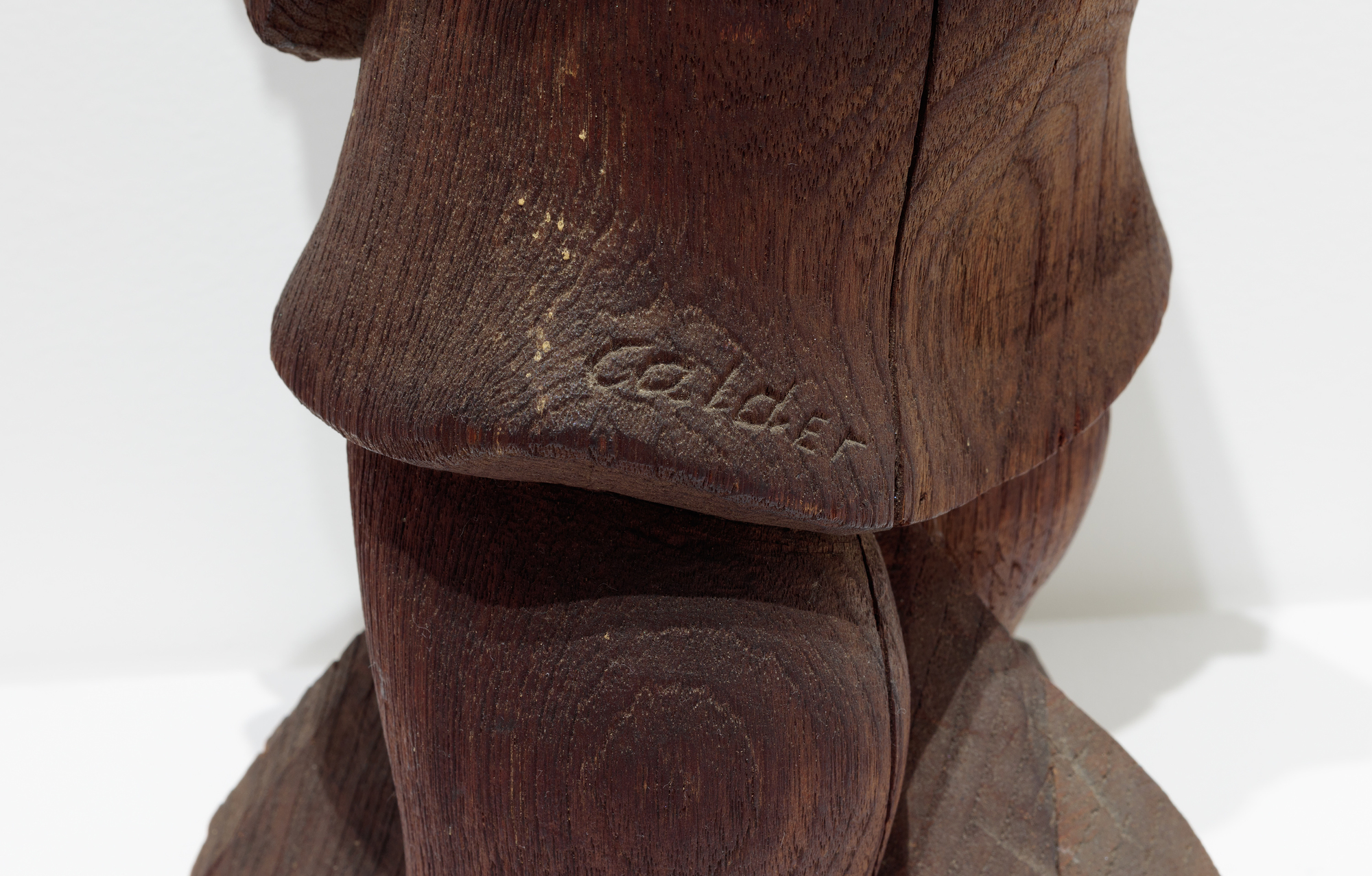 After disappointing sales at Weyhe Gallery in 1928, Calder turned from sculpted wire portraits and figures to the more conventional medium of wood. On the advice of sculptor Chaim Gross, he purchased small blocks of wood from Monteath, a Brooklyn supplier of tropical woods. He spent much of that summer on a Peekskill, New York farm carving. In each case, the woodblock suggested how he might preserve its overall shape and character as he subsumed those attributes in a single form.  There was a directness about working in wood that appealed to him. Carved from a single block of wood, Woman with Square Umbrella is not very different from the subjects of his wire sculptures except that he supplanted the ethereal nature of using wire with a more corporeal medium.
<br>© 2023 Calder Foundation, New York / Artists Rights Society (ARS), New York